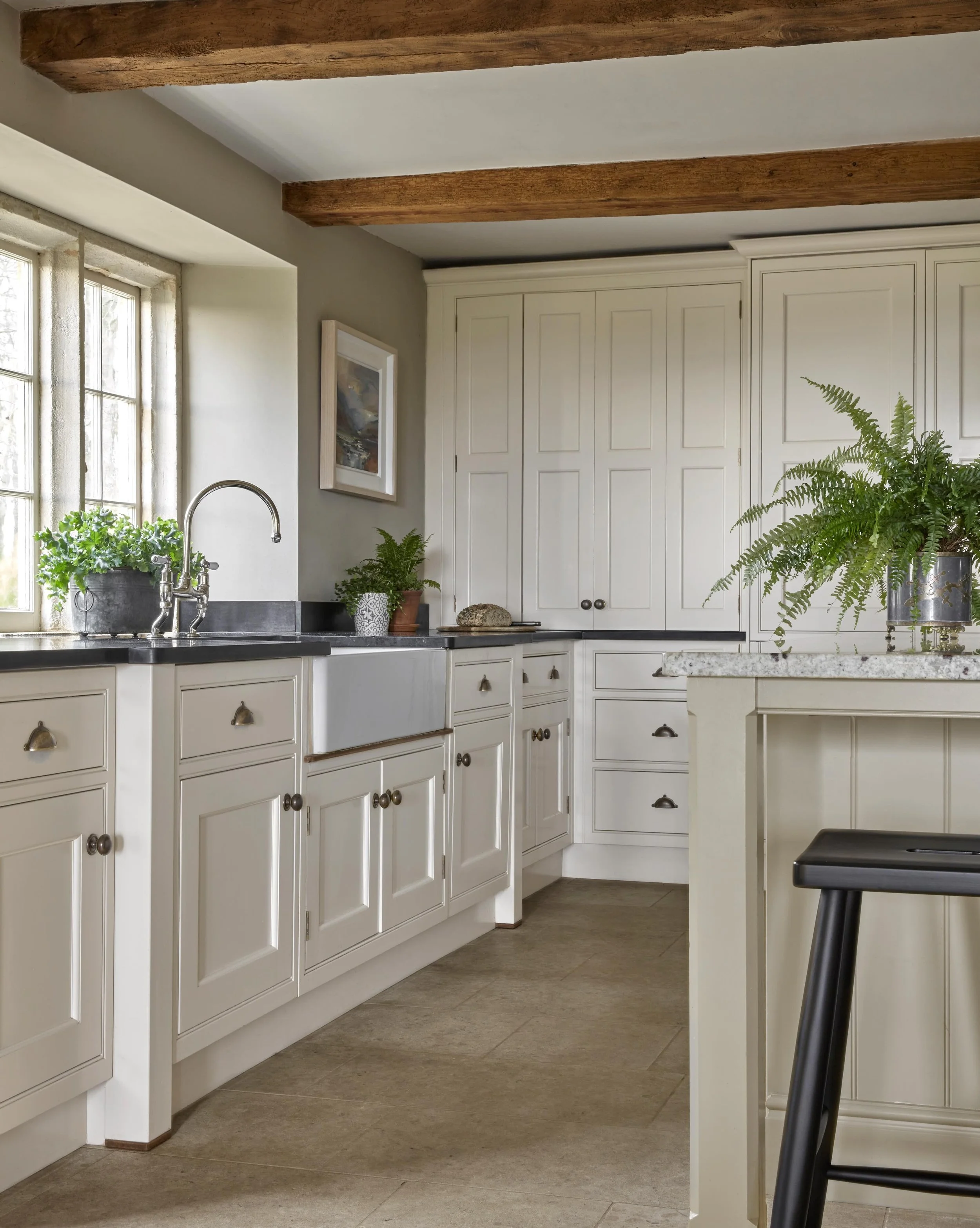 Crisp cool white in the summer heat. Original beams and mullion windows in our Cotswold farmhouse project are set off by the clean white kitchen and contemporary black bar stools. #kitchendesign #farmhousechic #kitcheninspiration #thecotswolds #kitch