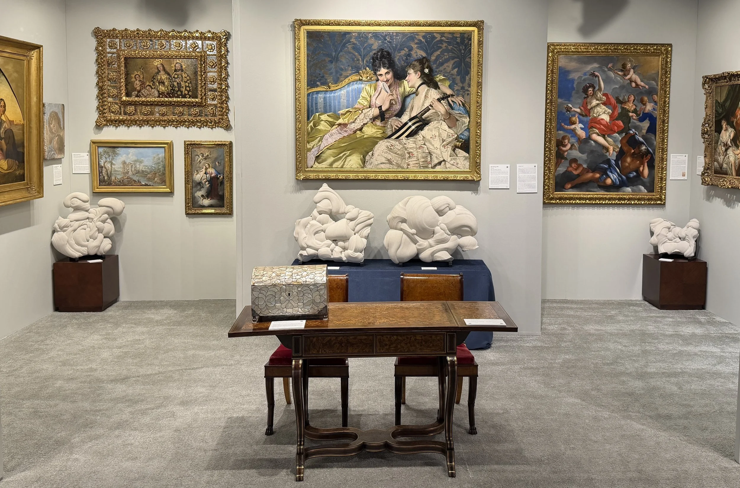 Art fair booth installed with paintings and decorative arts.