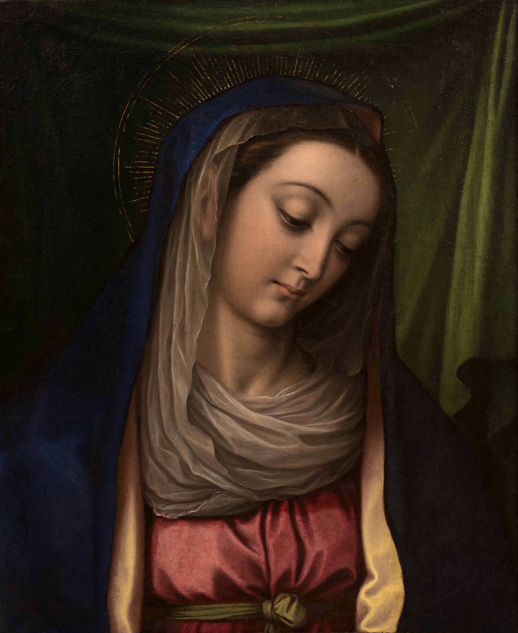 Haloed Virgin Mary in a veil with her head bowed and tilted to the right in front of a hanging green fabric