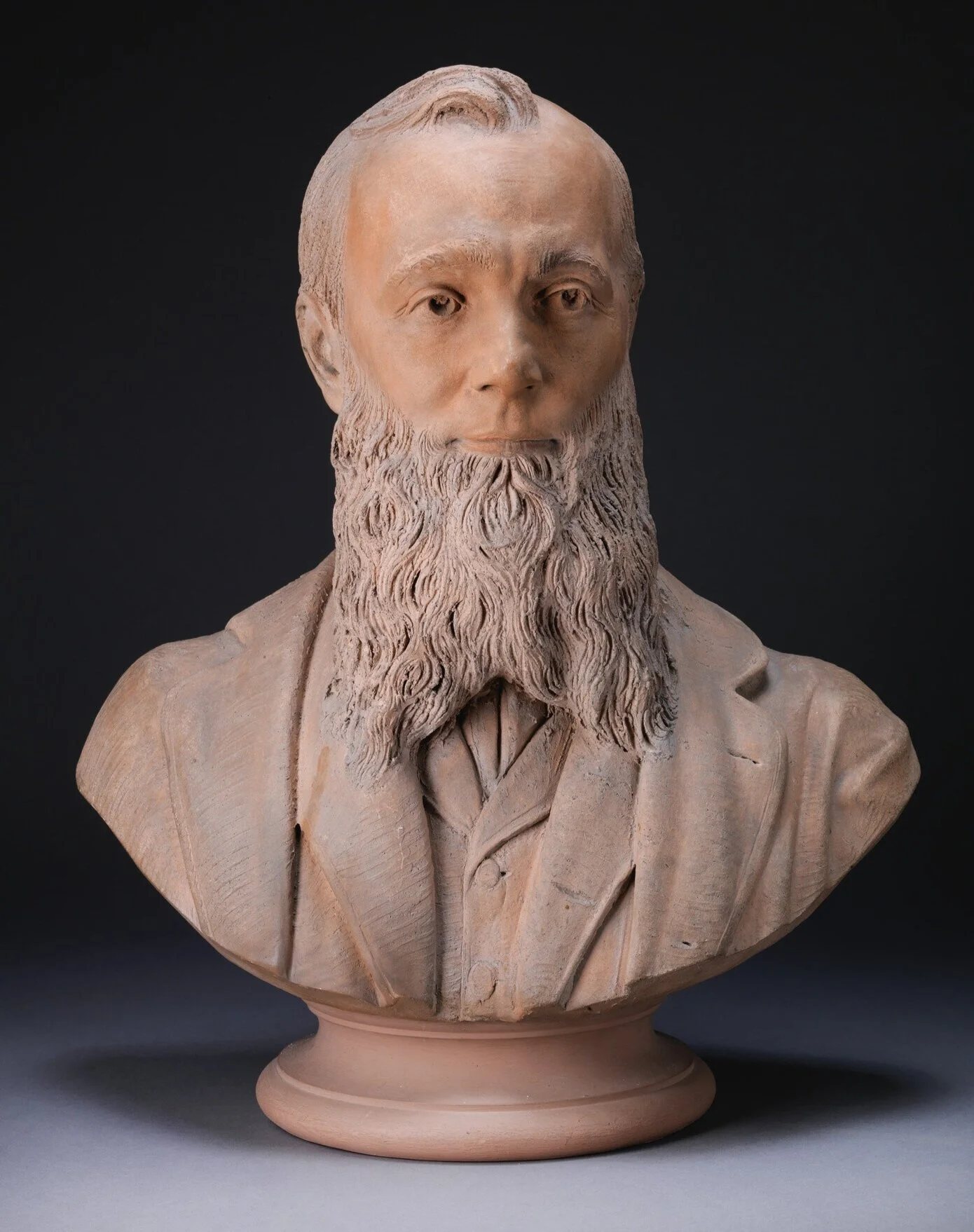 Bust of a beaded man without a mustache. Receding hairline.