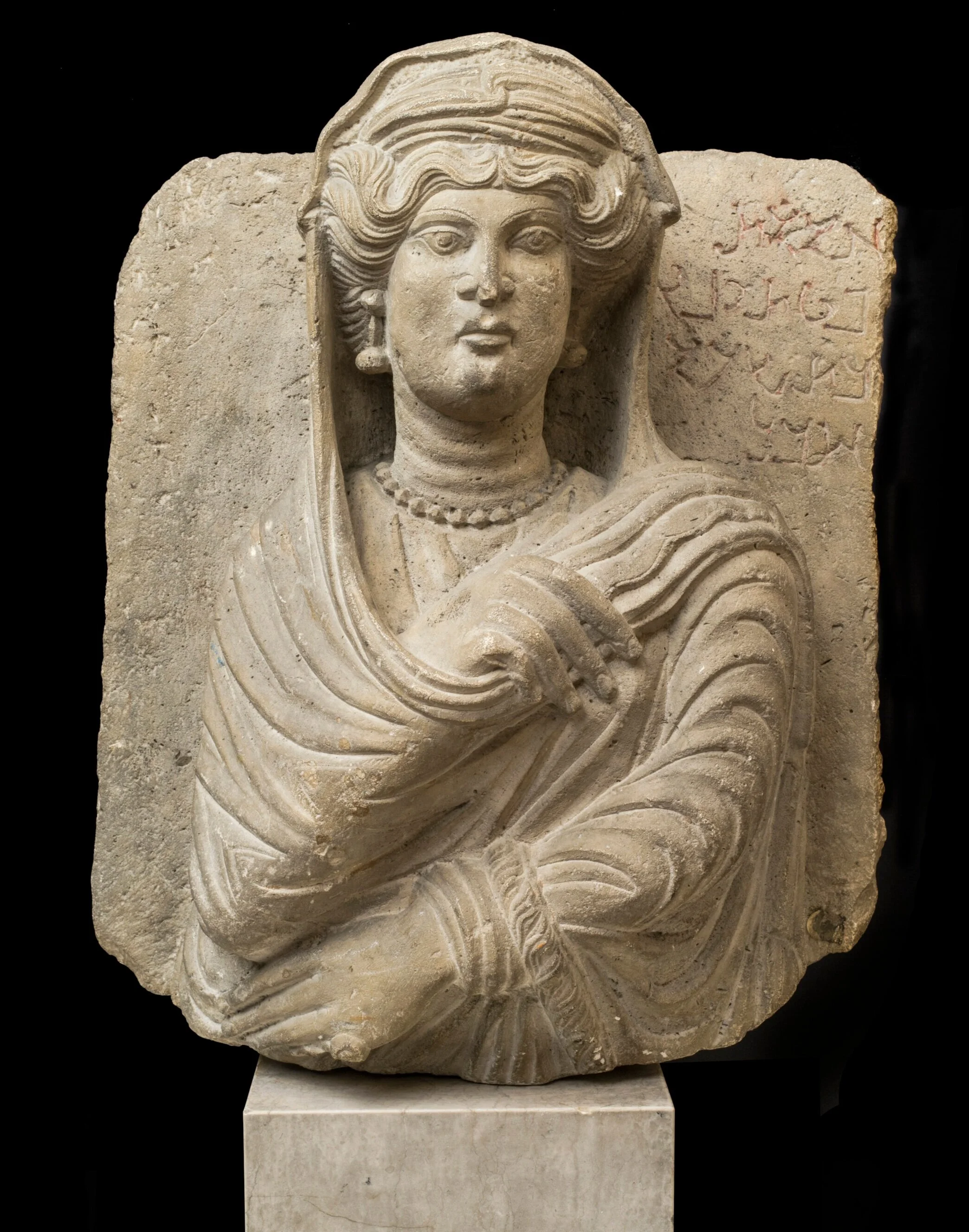 An ancient stone carving of a cloaked woman.