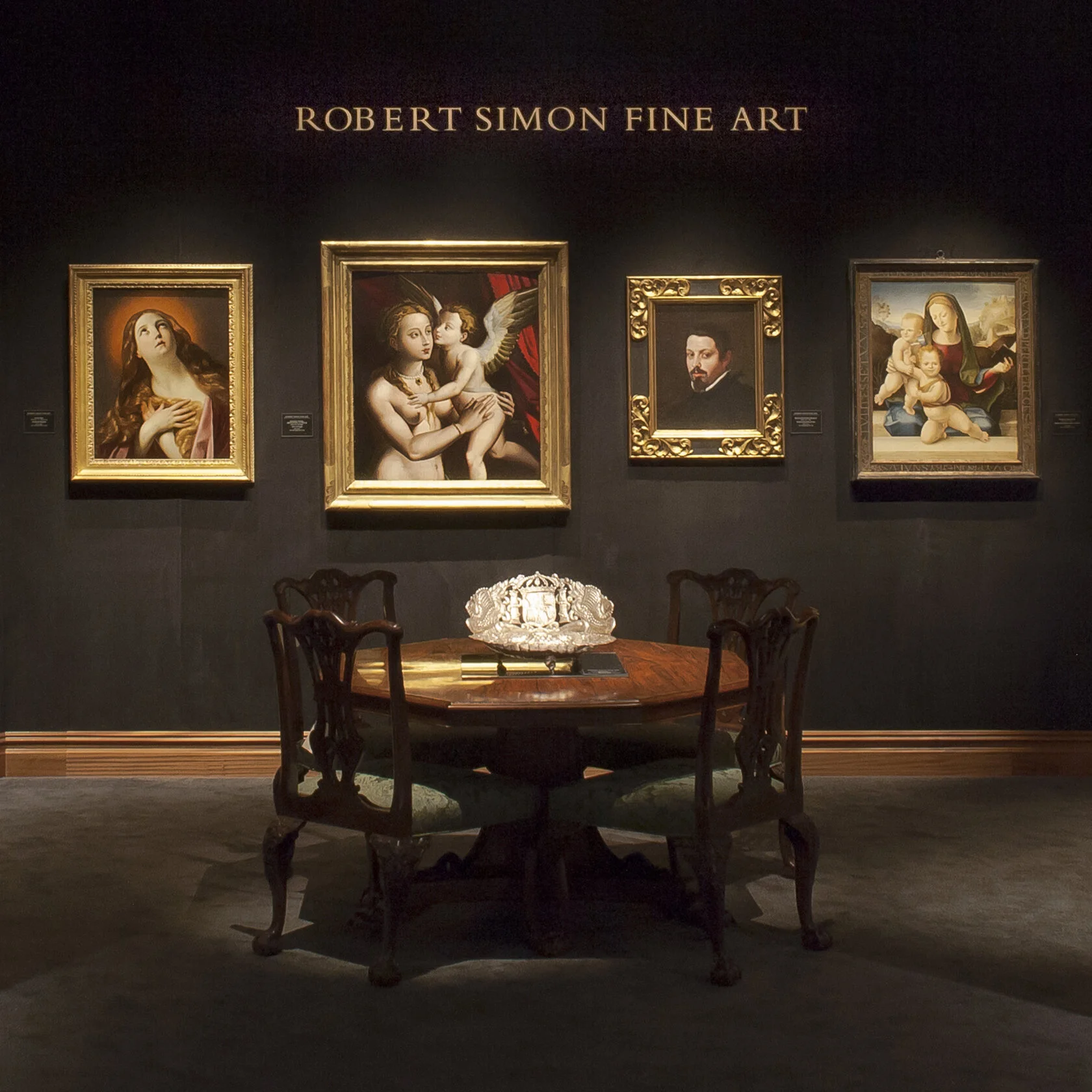 Front view of booth. Round table, flowers, four artworks.