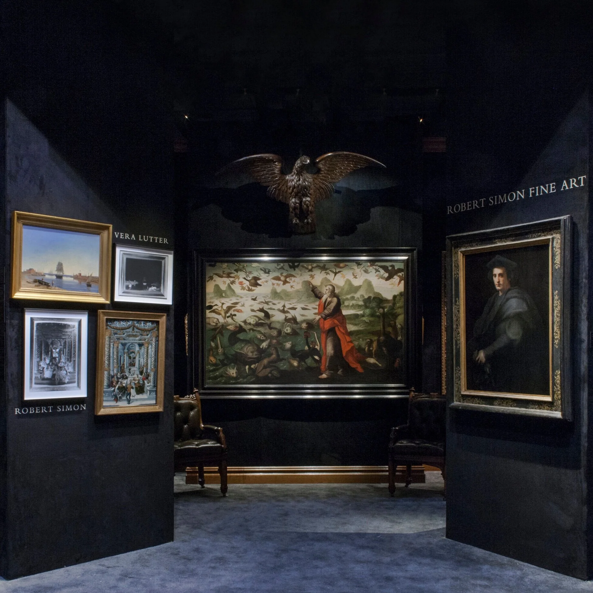 entry view of booth. Dark walls. On wall, large artwork with carved eagle.