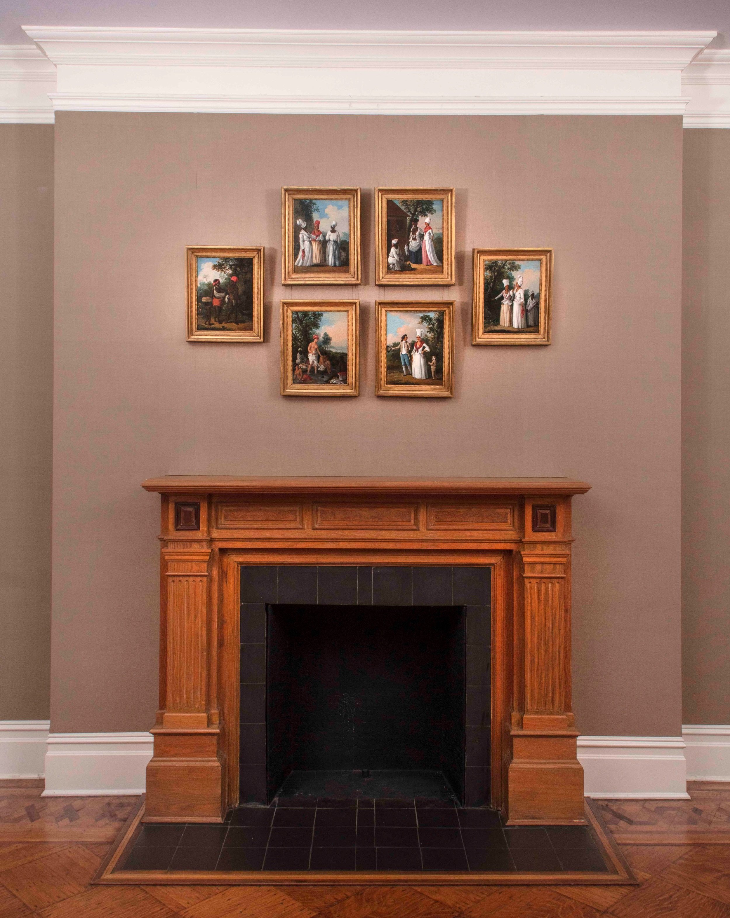 Six paintings by Agostino Brunias arranged over a fireplace.