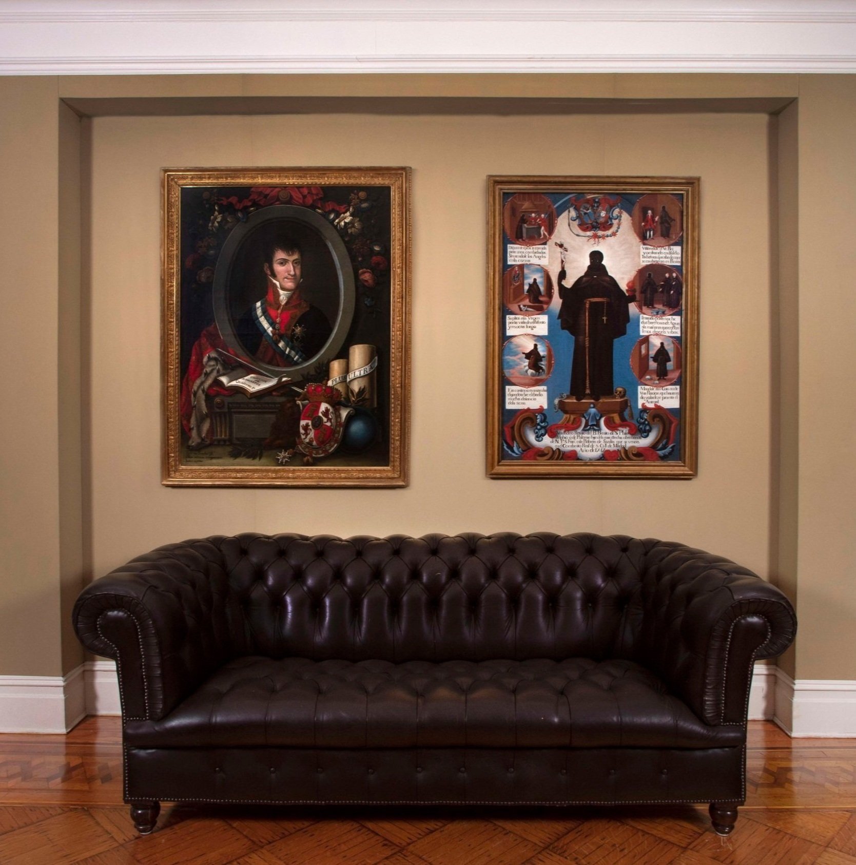 A portrait of Ferdinand VII by José Gil de Castro and a painting of Saint Benedict of Palermo above a sofa