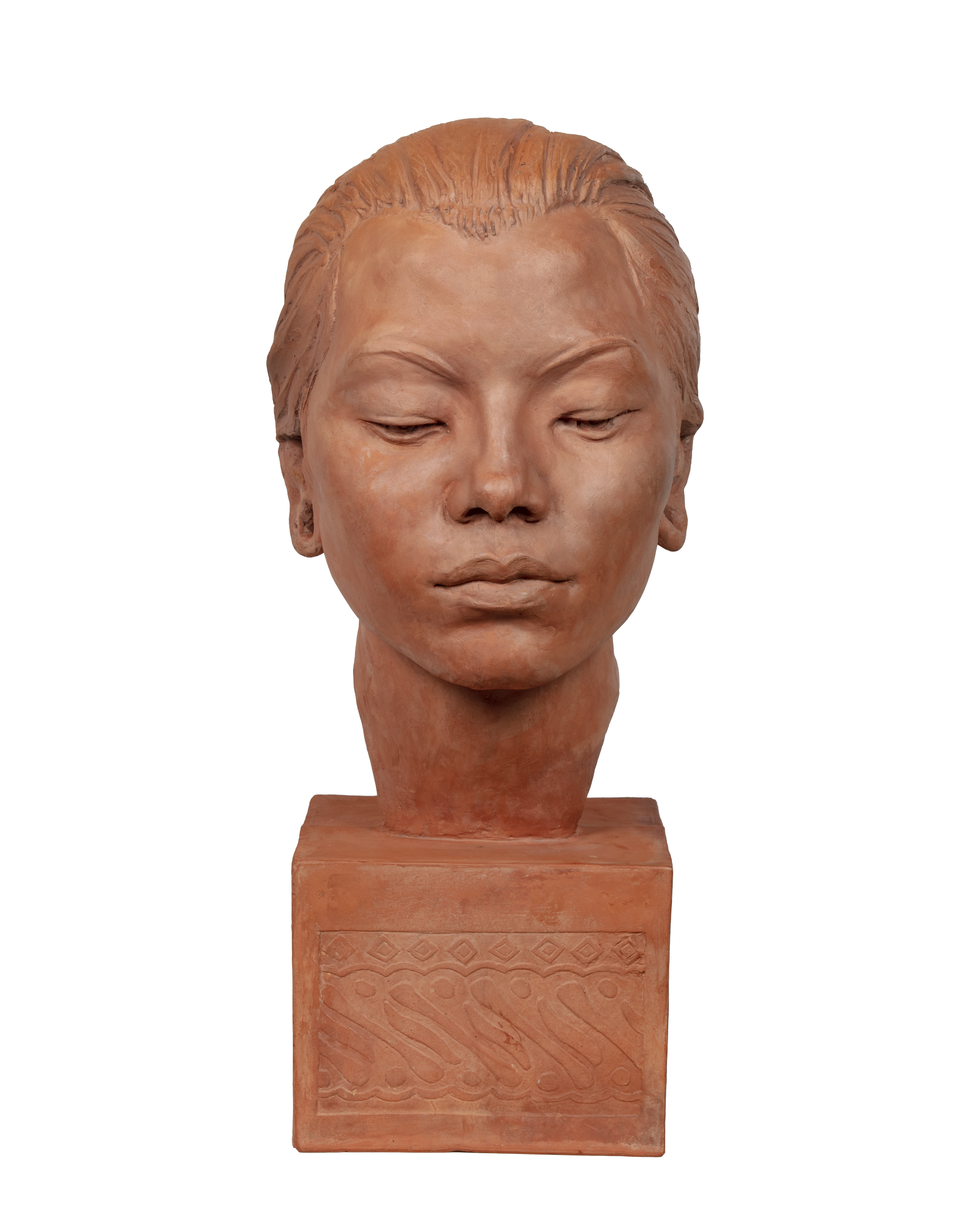 Terracotta sculpted face of a south asian female. Eyes closed. It rest on a square base. Her hair is gathered at the nape of her neck. 