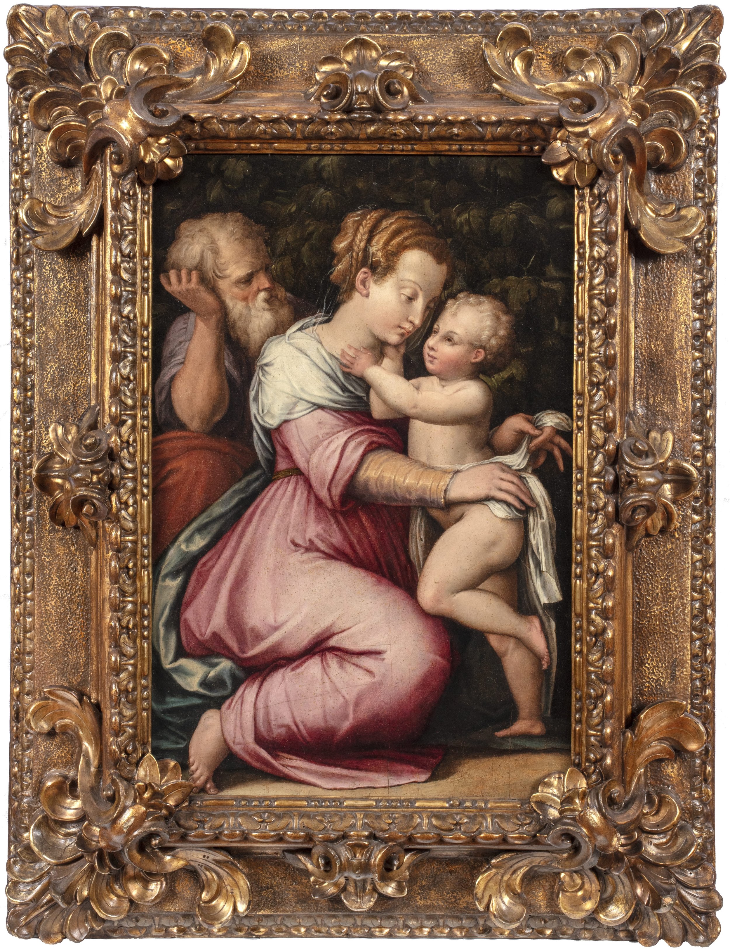 A young woman in a pink robe kneels and holds a nude child while an elderly bearded man looks at them from behind against a dark green background.