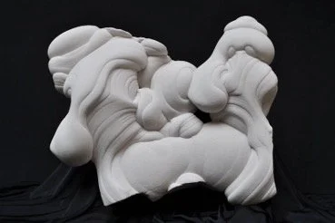 An abstract white sculpture with smooth, bulbous layers and an asymmetrical shape against a dark black background