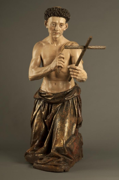 Half-naked man kneeling with habit tied around waist holds cross