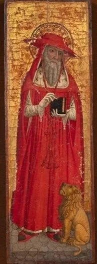 An elderly bearded man wearing red hat and robe holds a book in his hands against a gilded background wile a small lion sits next to him gazing at him.