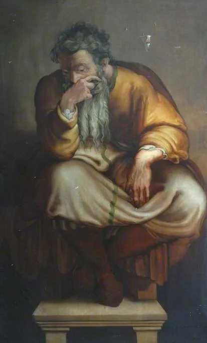 Bearded man seated holds hand on mouth