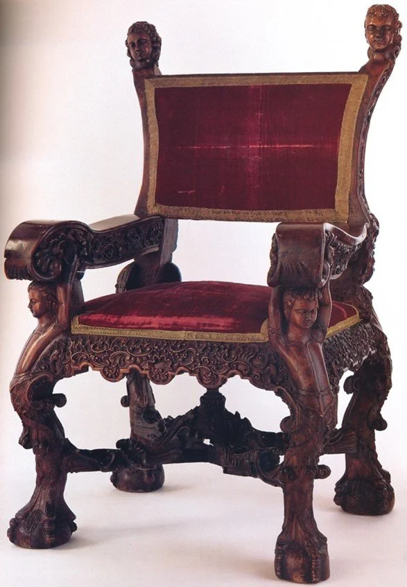 Red velvet wooden chair with gold embroidery, curved legs, cherubic busts, and decorative floral motifs