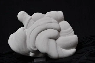 Reverse side of an abstract, white sandstone sculpture featuring interlocking, bulbous forms and a textured, swirled surface set against a dark black background
