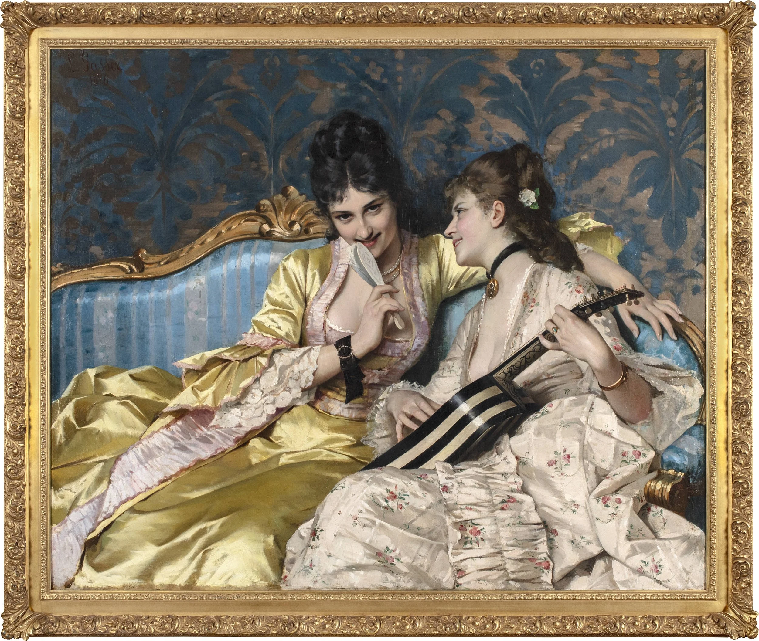 Two young women dressed in gowns sitting on a couch and one holding a guitar