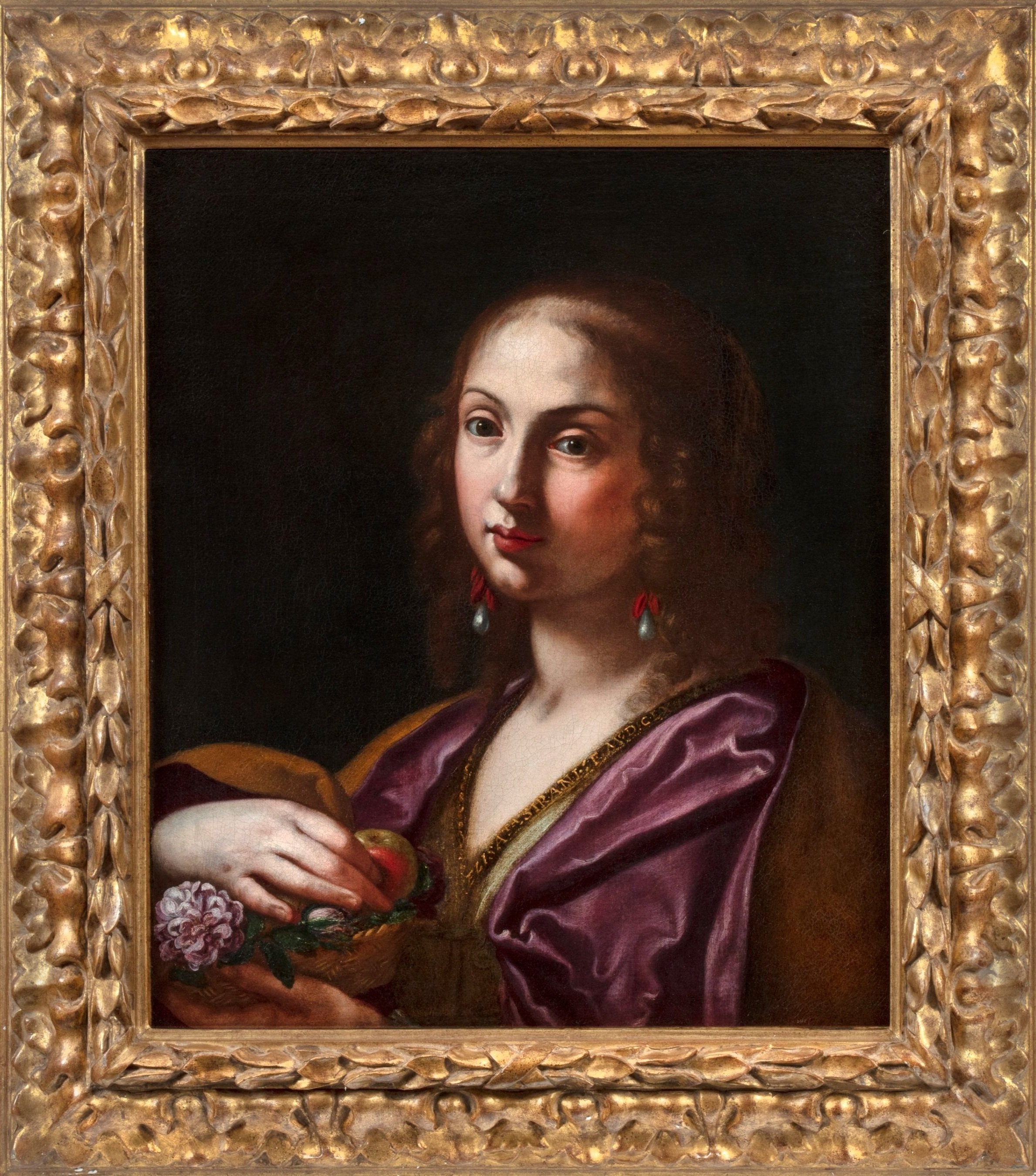 Portrait of a woman in three quarter profile. She looks toward the viewer as she holds an apple near her chest.
