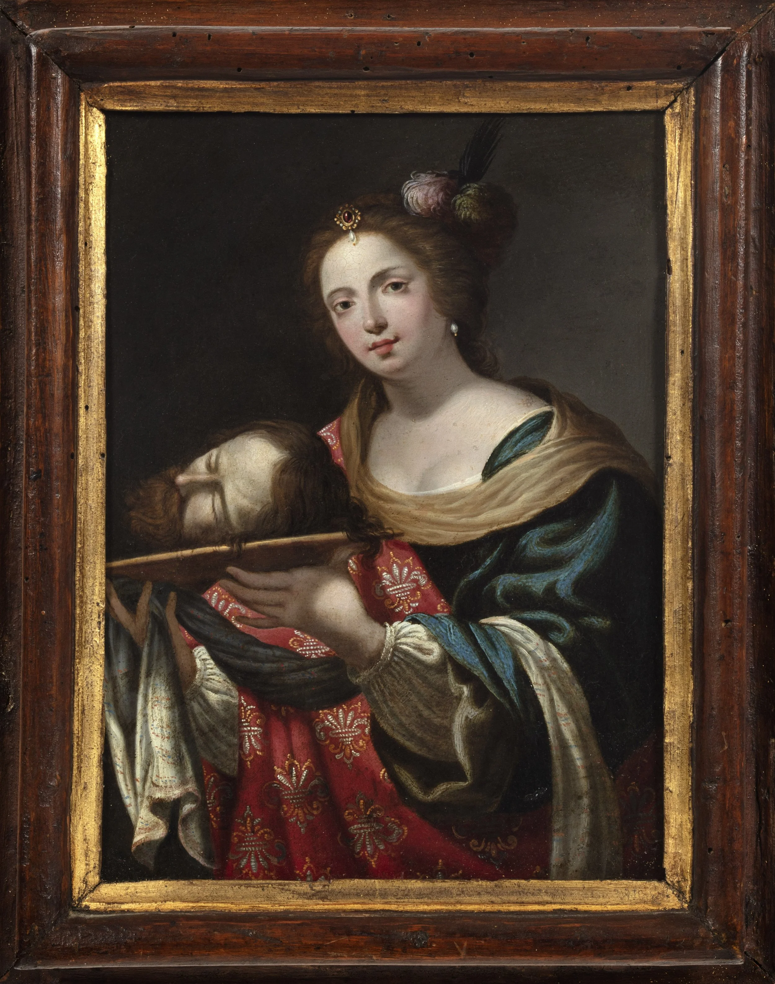 Young woman dressed in large, lush draperies, holding a platter with a severed head on it.