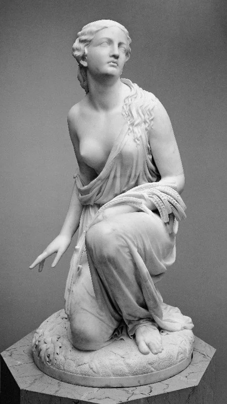 A sculpture of a half-naked woman wears a robe kneeling and gazing at the top-right corner.