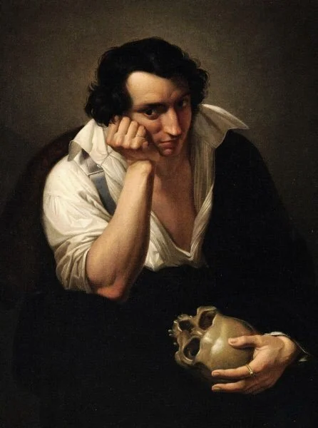 Male seated, right arm rests on bent leg, and his left hand cups a skull.