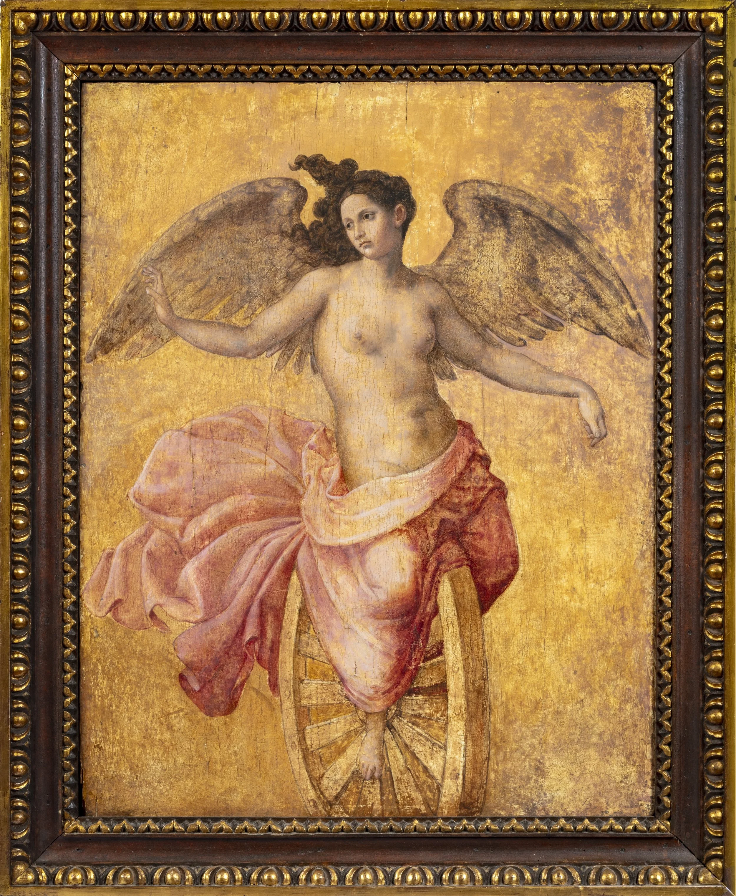 Winged and half naked woman sitting on a wheel