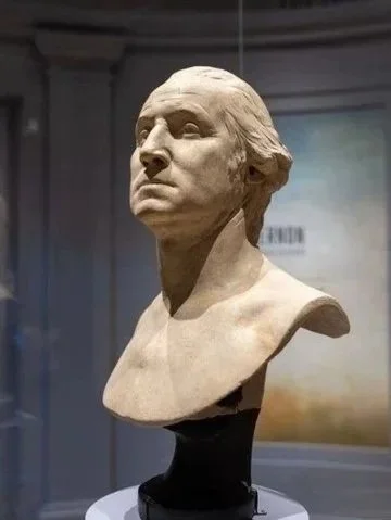 Heroic image of a sculpted bust of a man in a museum setting.