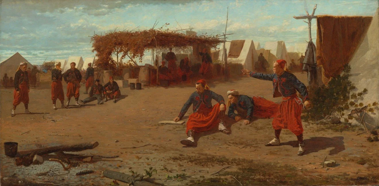 Soldiers wearing red tasseled caps, blue filigreed jackets, and baggy trousers in a camp: some standing and some sitting on the ground.
