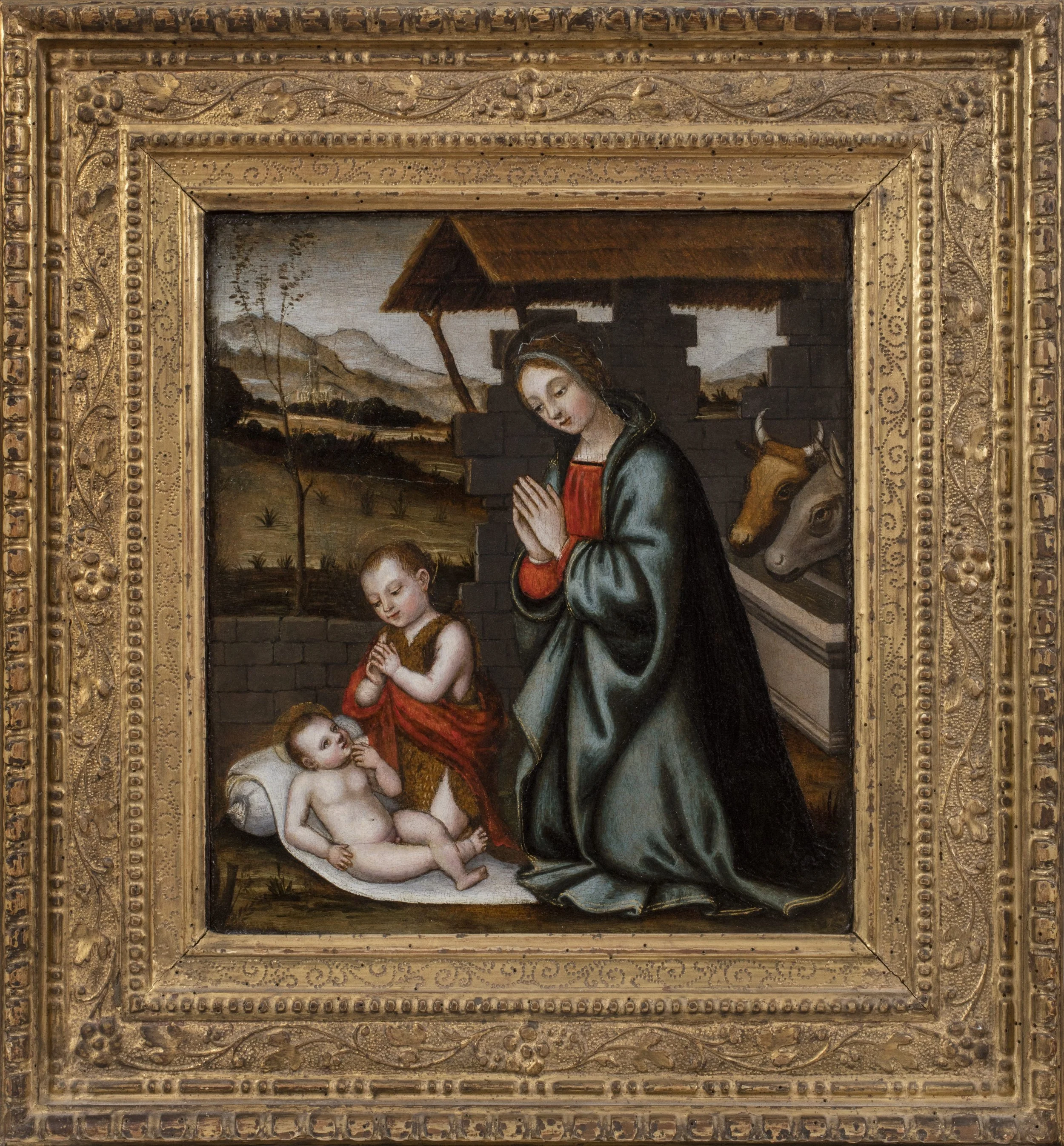 Madonna and the Infant Saint John the Baptist kneel and adore the Infant Christ in a stable with ox and donkey