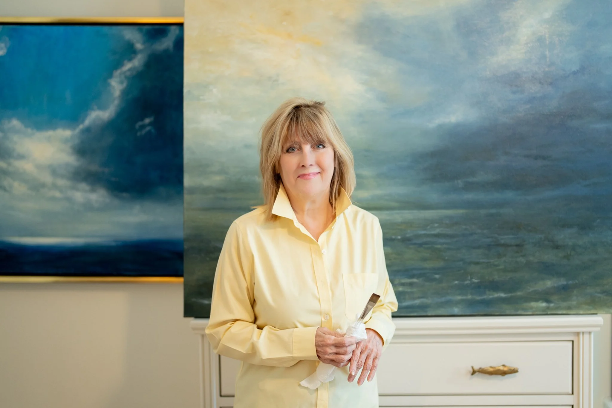 Photograph of the artist with two of her paintings.