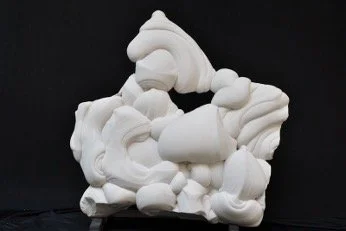 An abstract, white sandstone sculpture with a rough triangular silhouette set against a black background