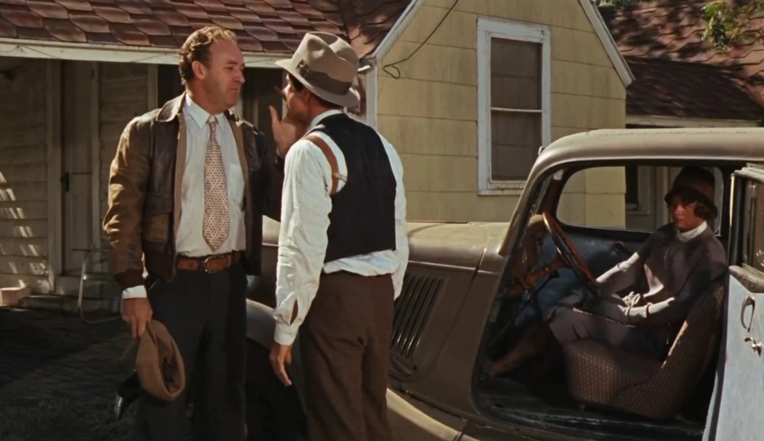 Hackman: Brown leather jacket, white dress shirt, print tie, brown belt and slacks.