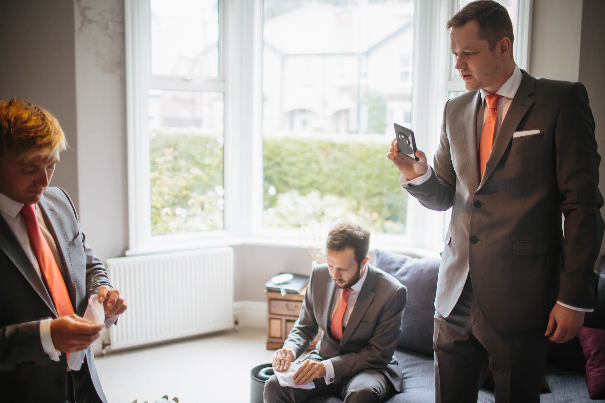 Groomsmen looking at their phones and folding pocket squares