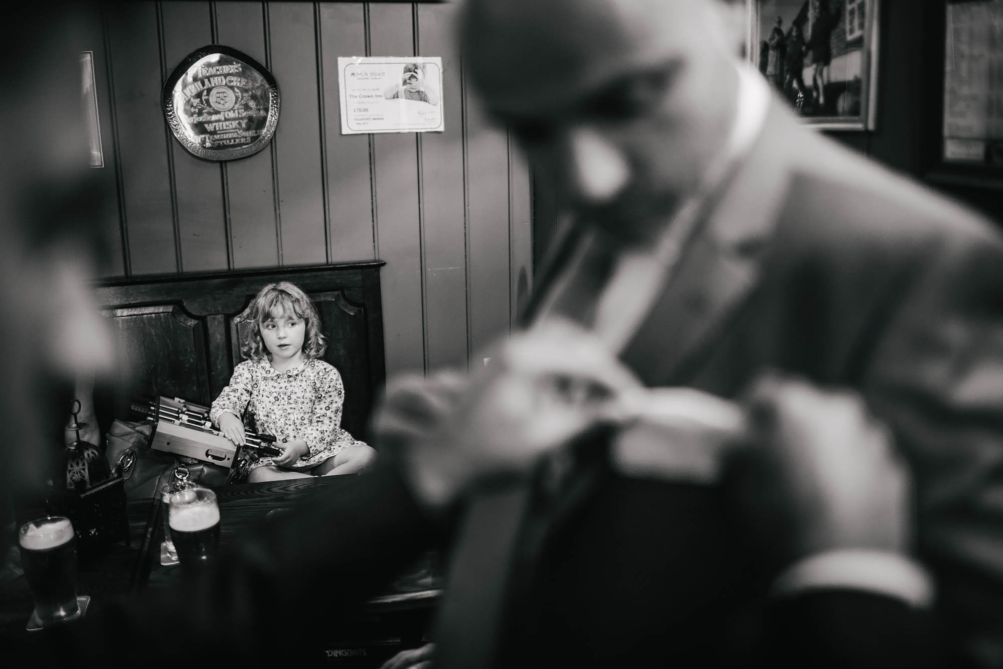 Young girl looks on as man has help with his pocket square