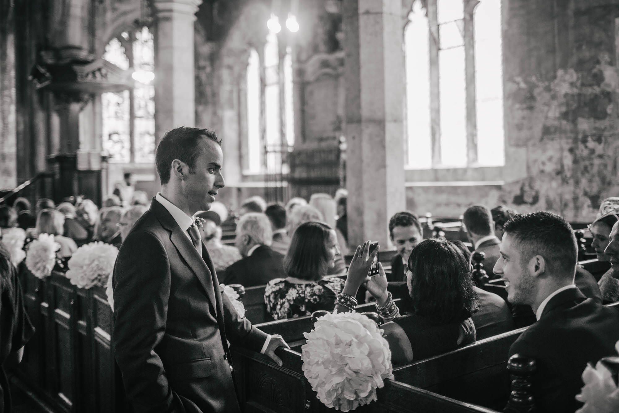 Groom chatting to guests in the church at his wedding in Yorkshire