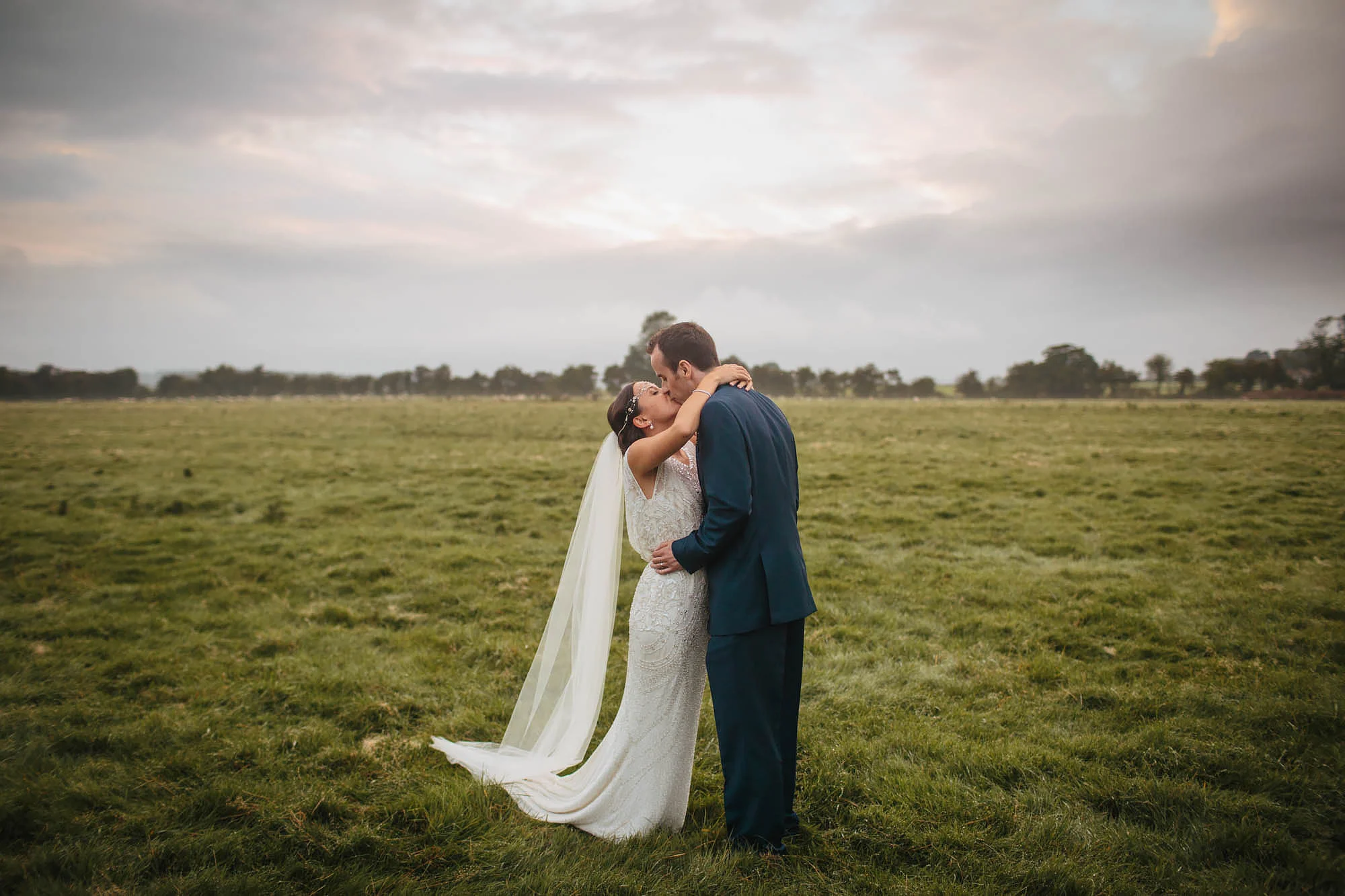 Bride and groom kissing in a field at Hornington Manor