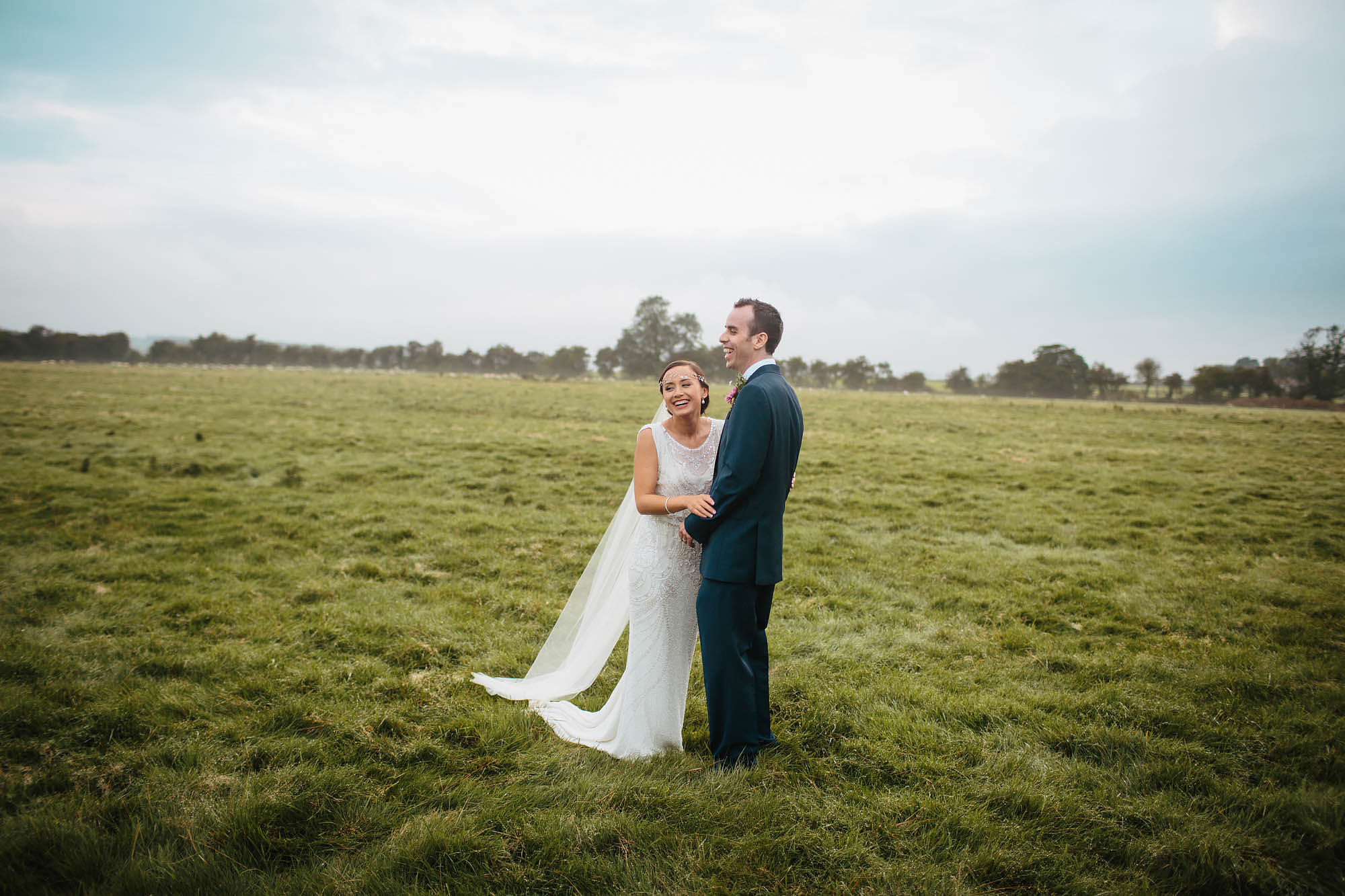 Bride and groom laughing in a field at Hornington Manor