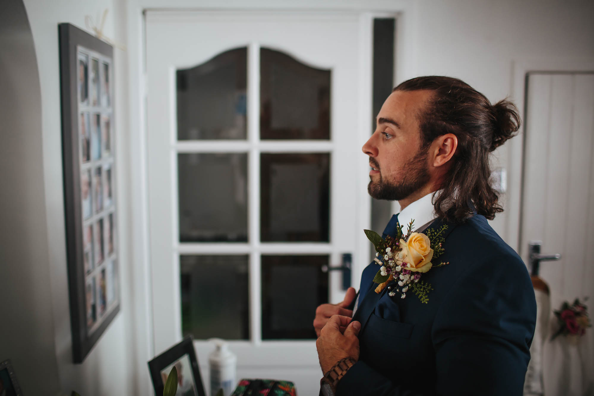 Groom looking in the mirror getting ready on his wedding day