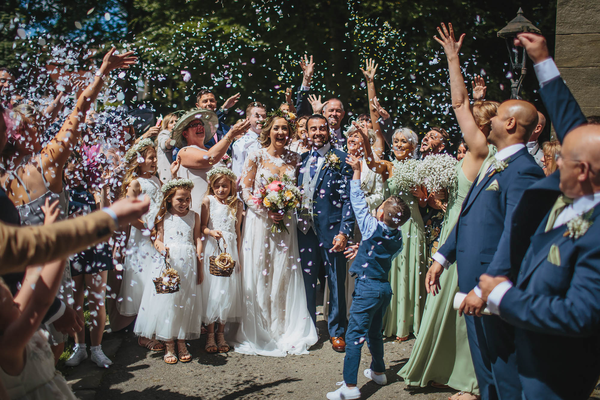 Wedding guests throw confetti over the bride and groom