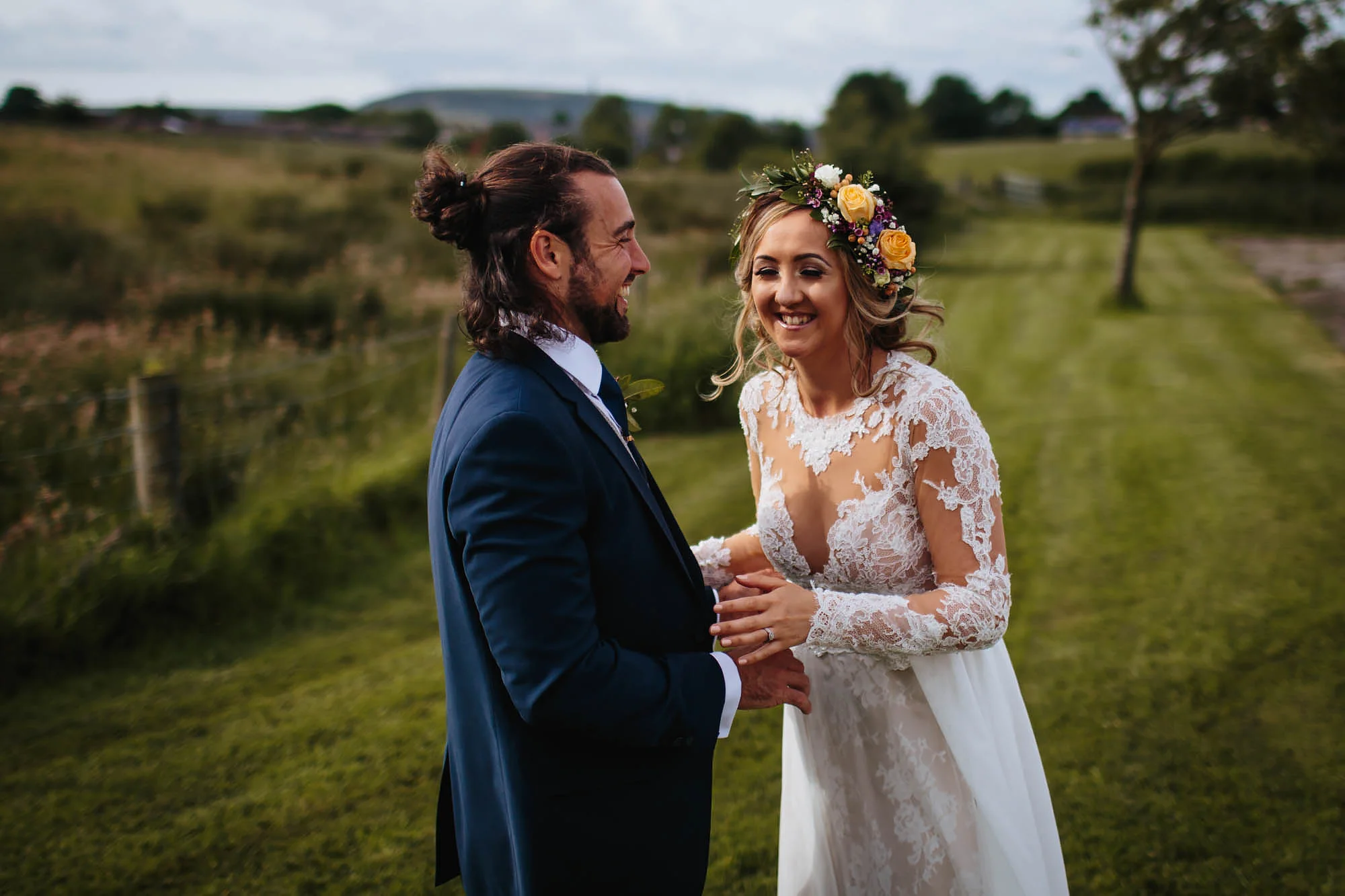 Bride and groom laughing in fields on their wedding day