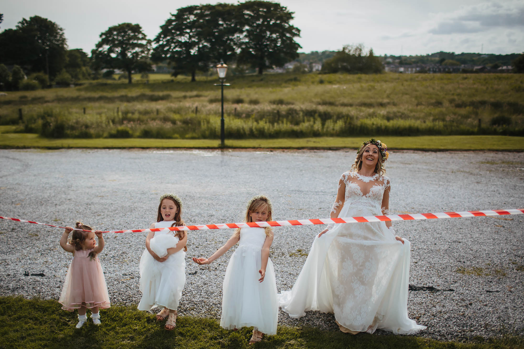 Bride and bridesmaids limbo under red tape at a wedding