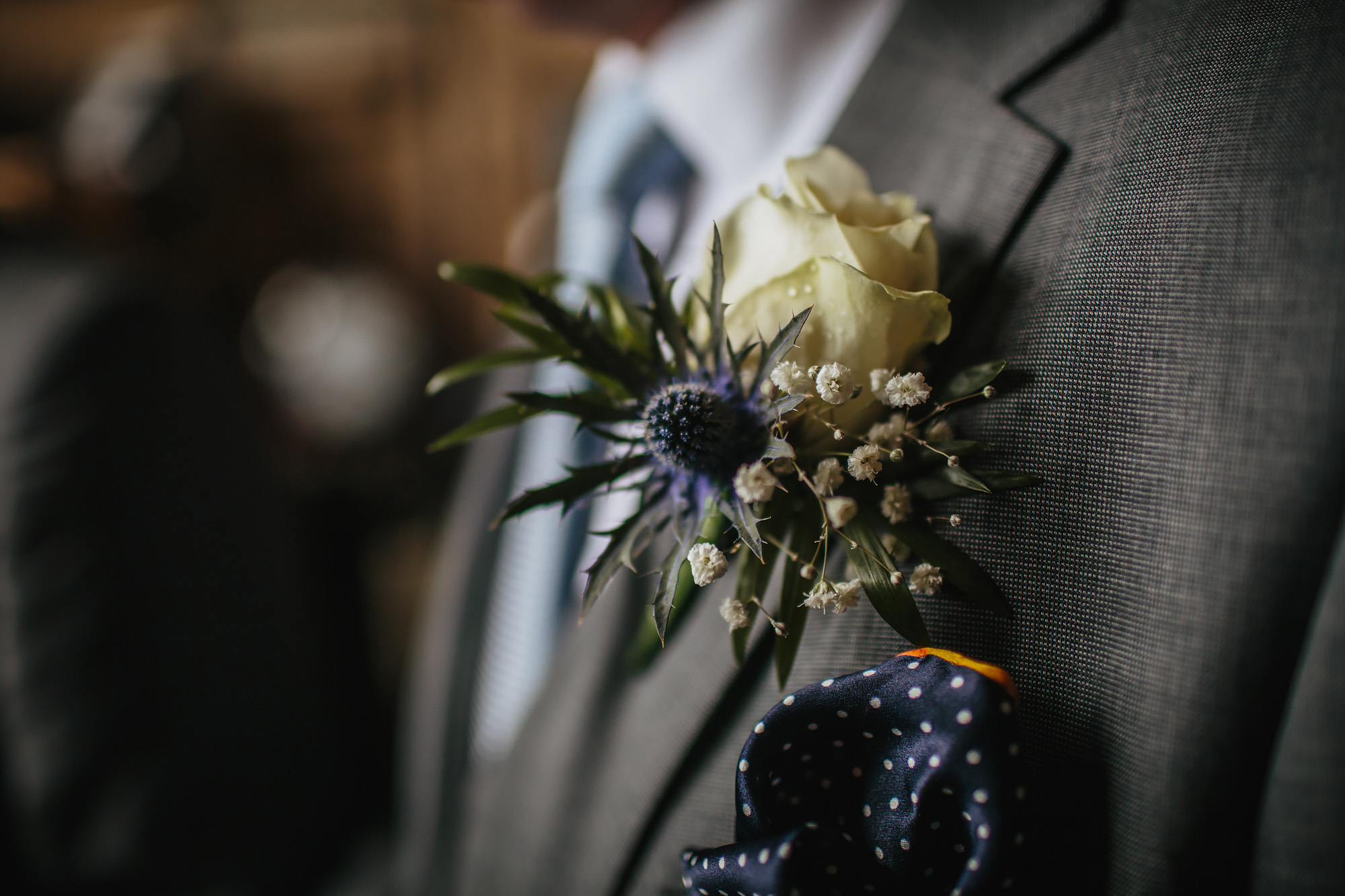 A close up of the grooms buttonhole on his suit