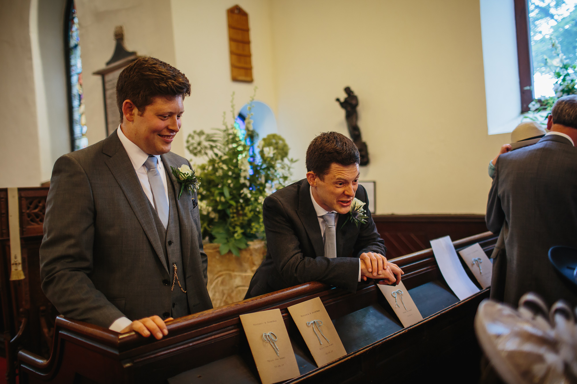 Groom and best man laughing at the church at a wedding