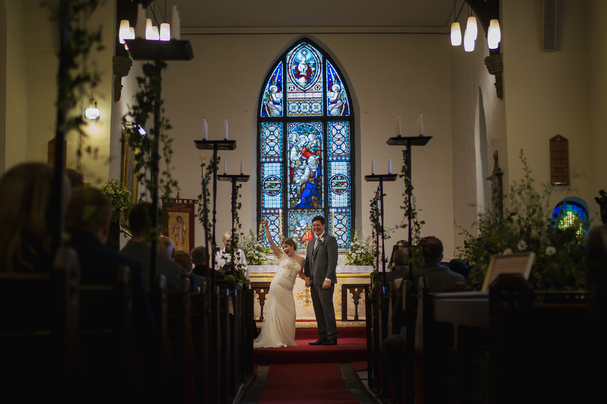 Bride and groom happy at their church ceremony in front of a stained glass window