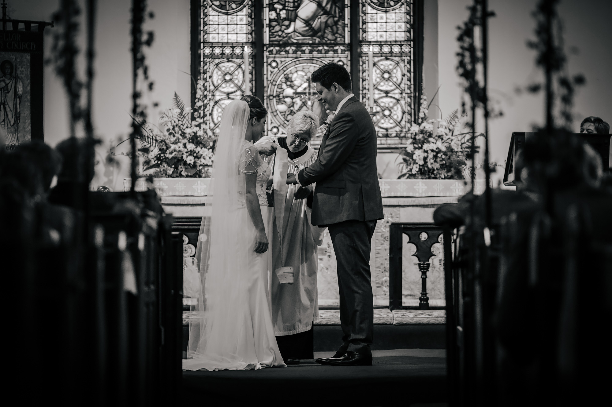 Vicar tying hands of the bride and groom during the wedding ceremony