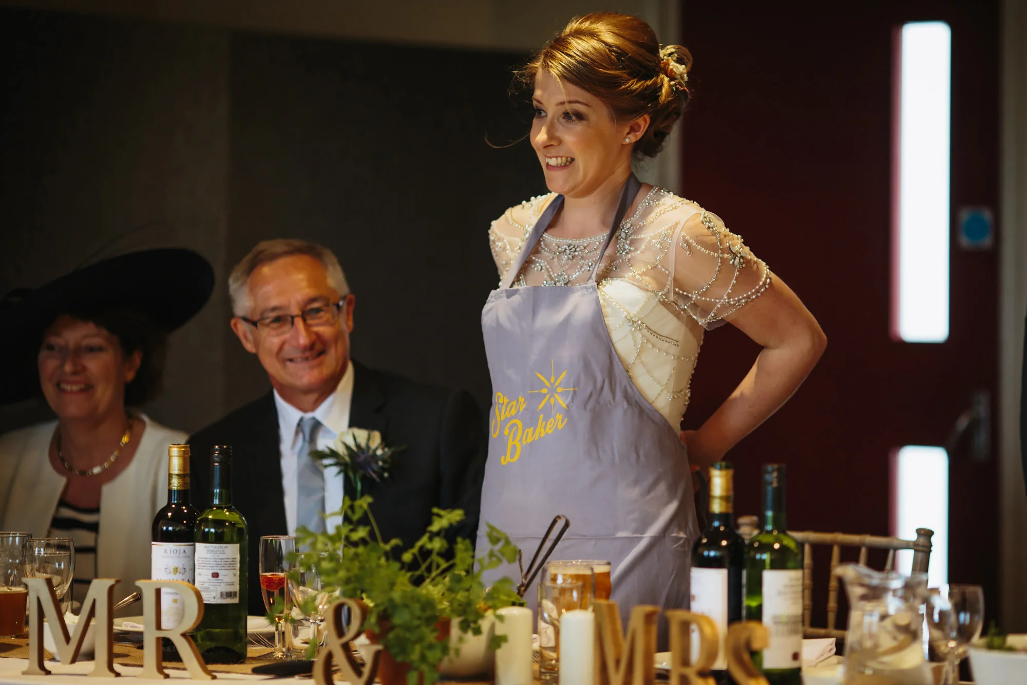 Bride wears a star baker apron on top of her wedding dress