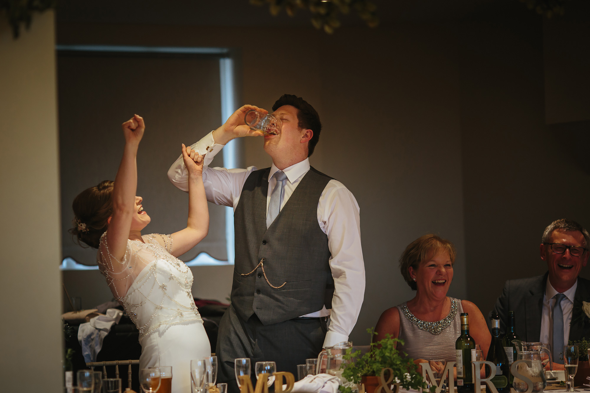 Groom drink a pint and his wife celebrates at a village hall wedding