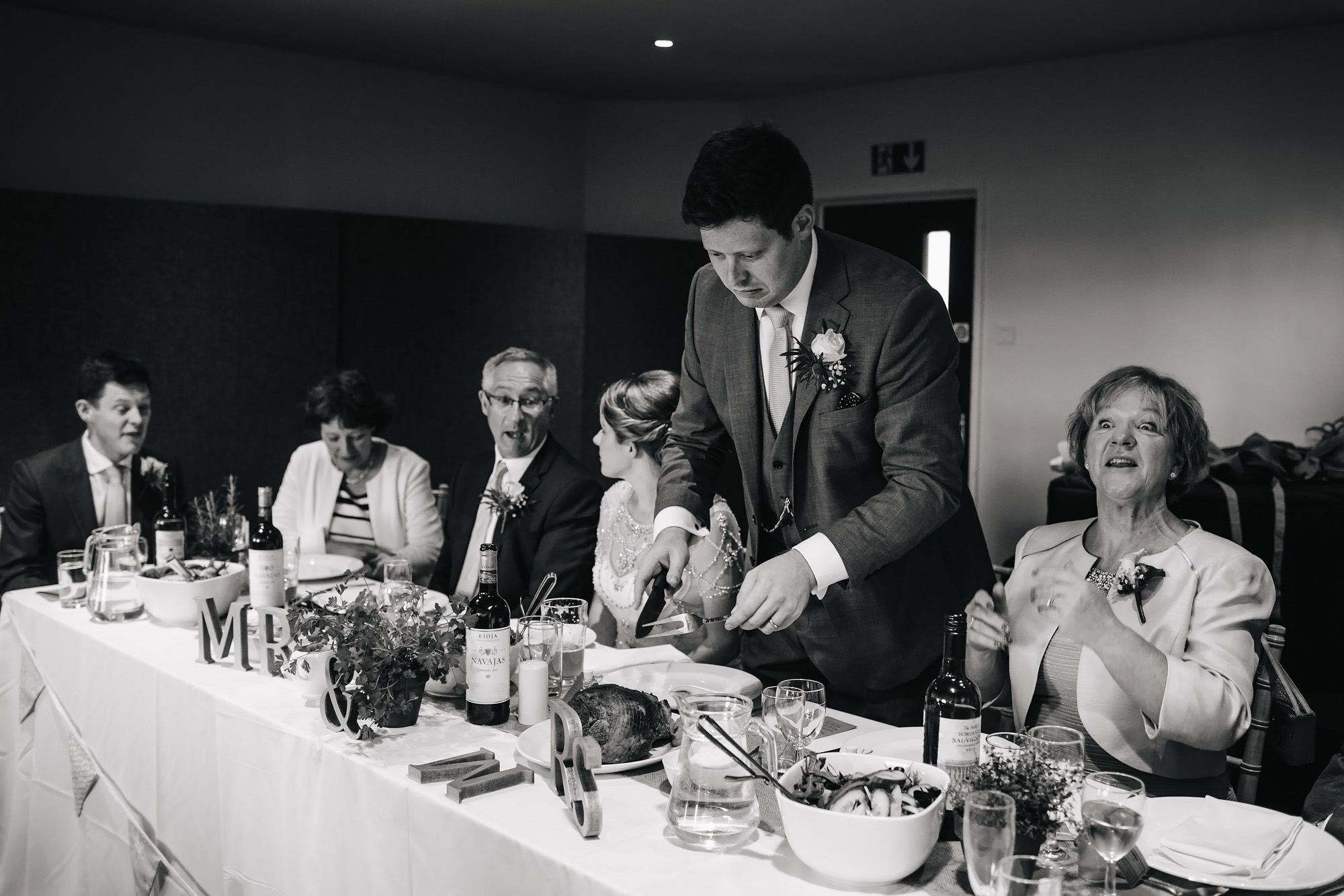 Groom carving meat at the top table on his wedding day