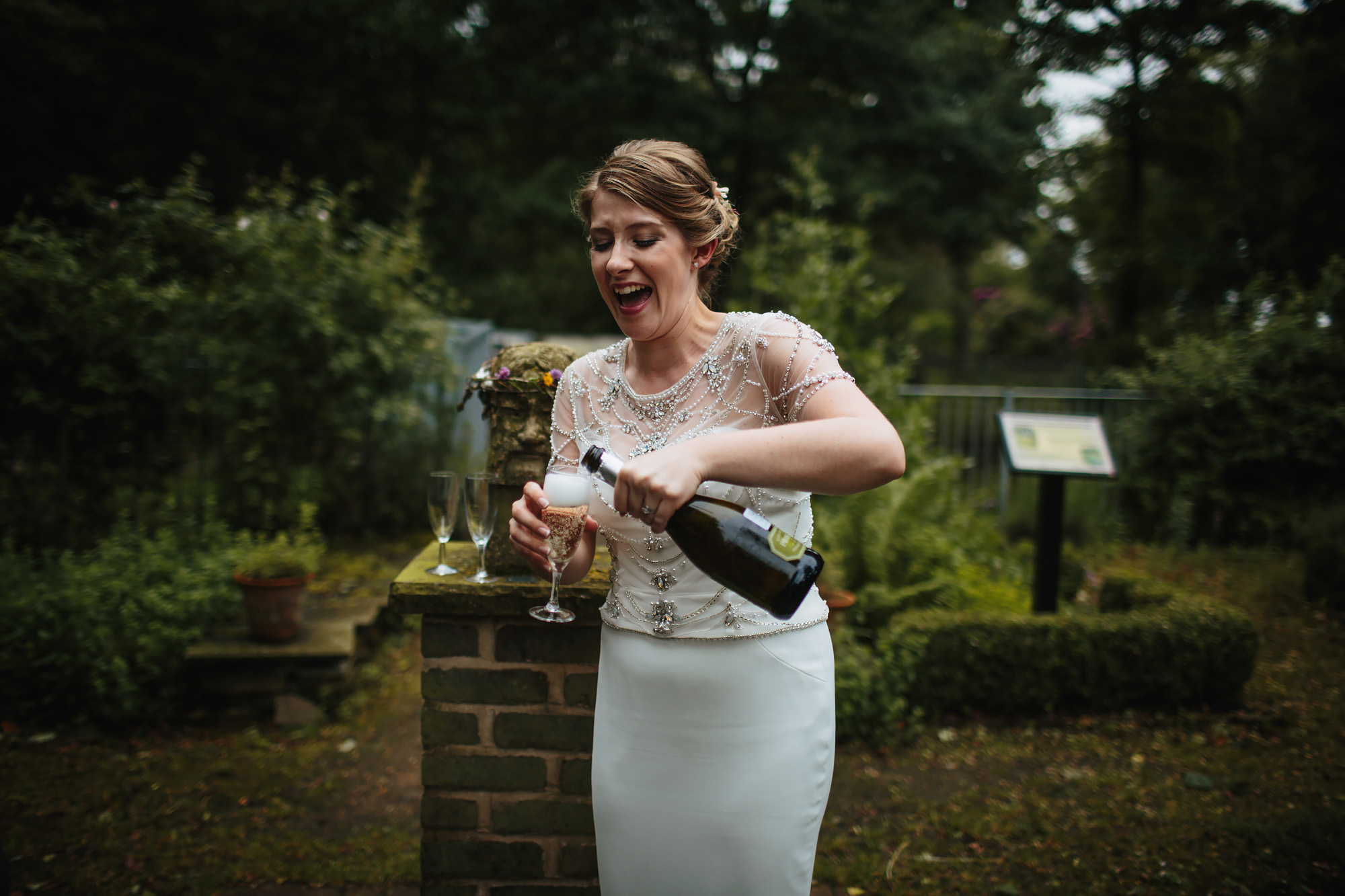 Bride laughing while she pours a glass of champagne