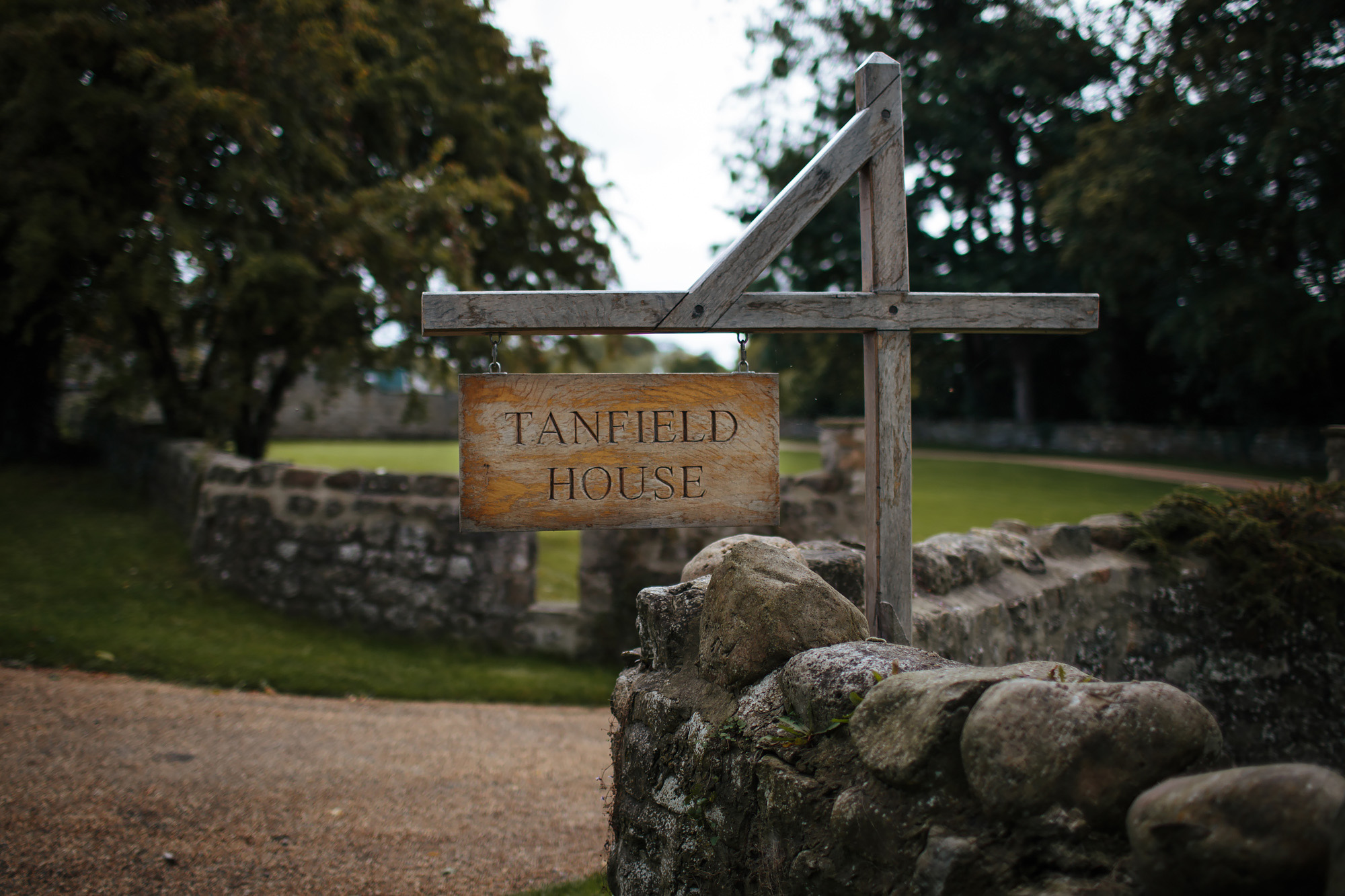 Wooden sign for Tanfield House by brick wall