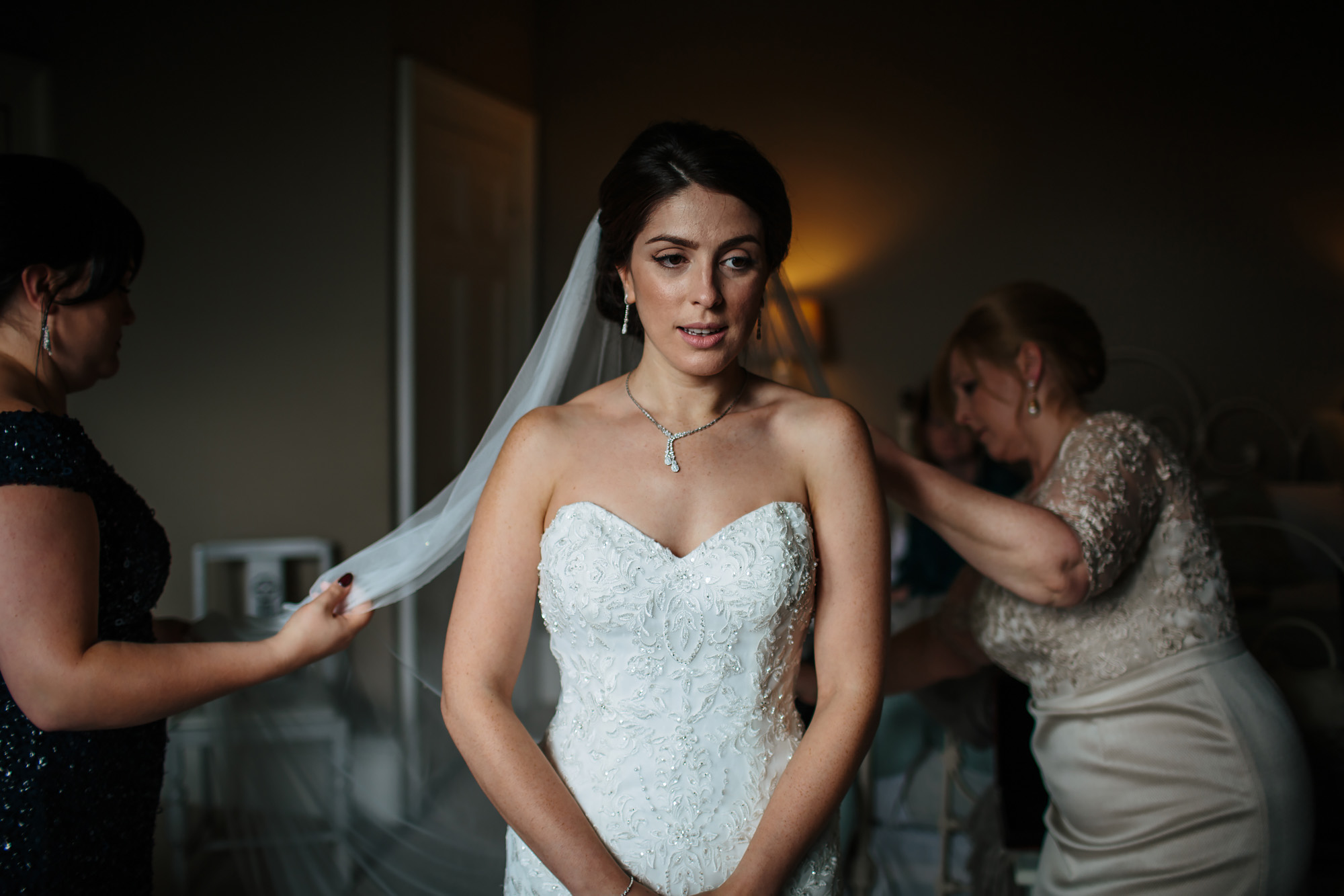 Mother and bridesmaid help put the brides wedding veil on