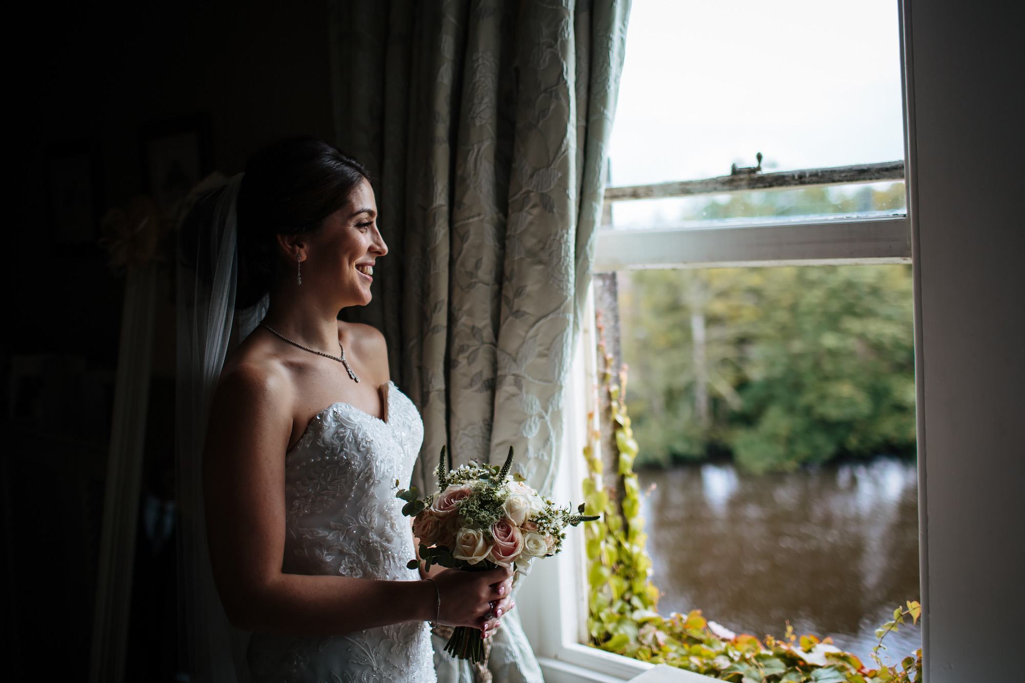 Bride holds her flowers by the window on her wedding day