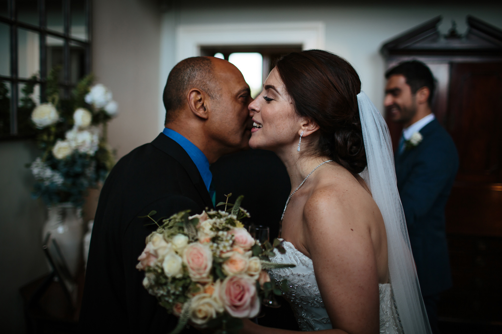 Bride with flowers kissing guest at her wedding